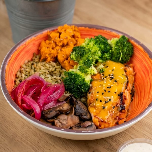 A colorful poke bowl with salmon, broccoli, sweet potato, pickled onions, mushrooms, and rice.
