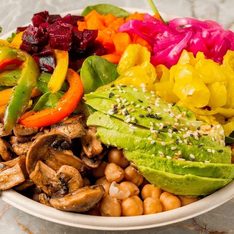 Colorful vegan bowl with avocado, chickpeas, mushrooms, peppers, beets, and pickled onions.